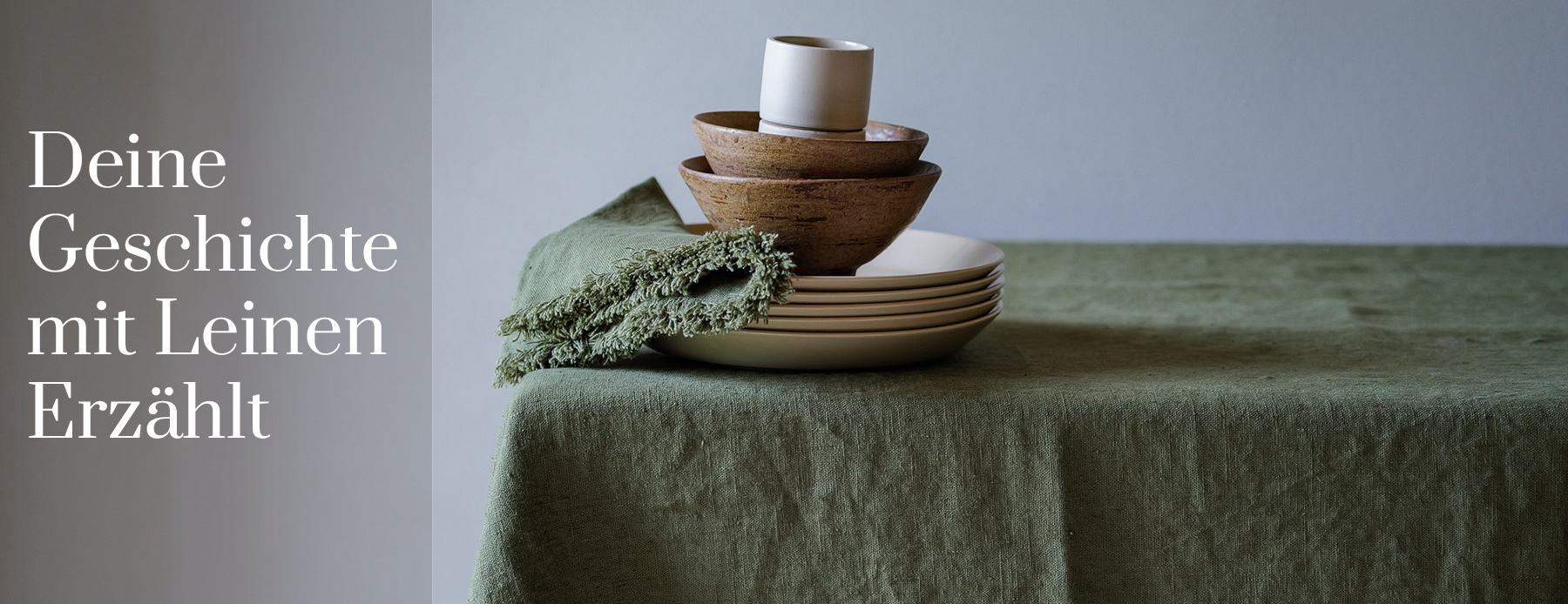 Deine Geschichte mit Leinen erzählt – grüne Leinentischdecke und Servietten mit Keramikschalen.