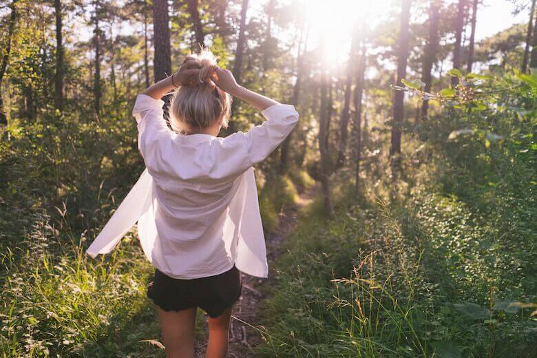 Frau in weißem Hemd und Shorts im Wald